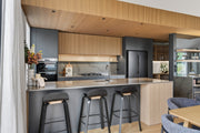 Modern kitchen with island, bar stools, and a view into another room. oak panel 